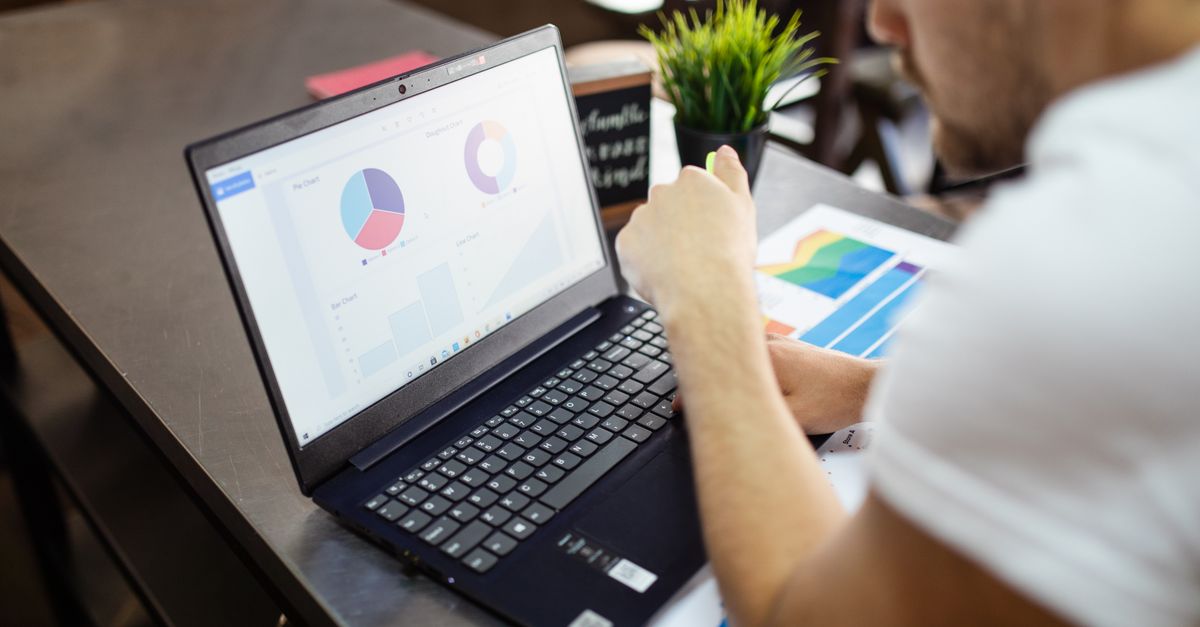 Man reviewing charts and graphs on a laptop for data analysis.